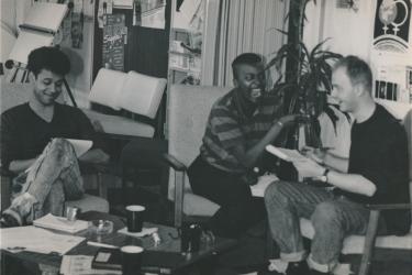 Keith Trotman, Colleen Humphrey and Jamie McCarthy working at the Greenwich Lesbian and Gay Centre, sitting at a coffee table, smiling and laughing