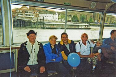 Four adults and a child sitting on the Pride Boat sailing past the Globe Theatre towards Westminster, 1998