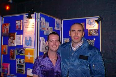 Two people standing in front of their HIV and sexual health outreach stall at the Long Yang club night, 1999