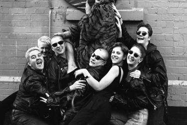 Group of volunteers gathered around Metro Thrust worker Julian Hows who is holding a large fabric heart, in the industrial estate outside The Metro Centre in 1994