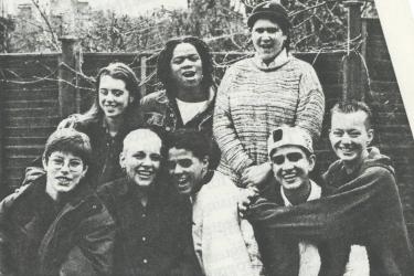 A group of eight young people smiling, hugging and laughing in a posed photograph for participants in the Young Women's Video Project