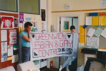 Two workers from the Greenwich Lesbian and Gay Centre holding up the organisation's banner in the Centre, 1989