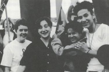 Group of four women smiling and hugging on board The Metro Centre's Greenwich Faerie boat to Pride, 1995