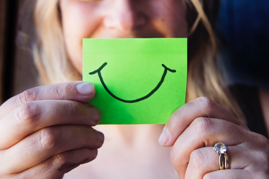 A woman holding a green card with a smile drawn on it