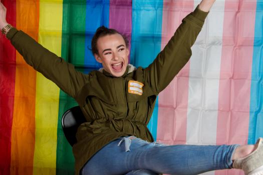 A young person wearing makeup in front of a trans flag at the METRO youth summit in Southwark