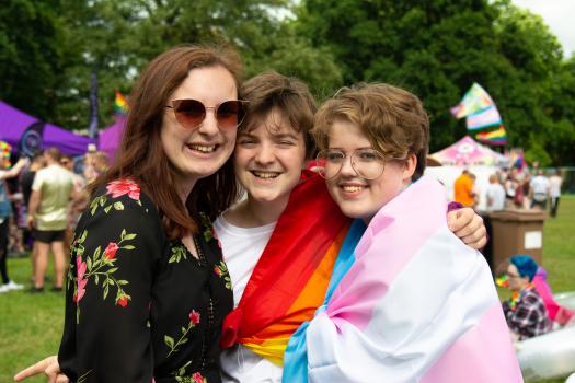 Three young people, one wearing a trans flag, at Essex Pride