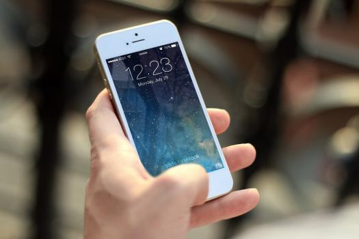 A hand holding a white iPhone with bokeh in the background