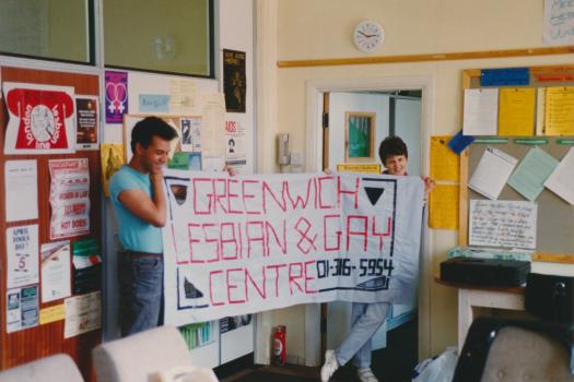 Two workers from the Greenwich Lesbian and Gay Centre holding up the organisation's banner in the Centre, 1989