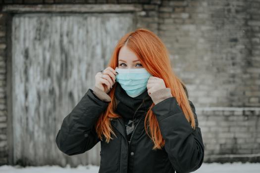 Red haired woman holding up a face mask