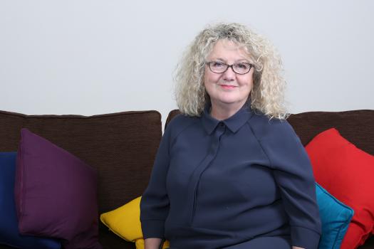 Photo of Alison on a sofa with colourful cushions