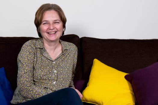 Photo of Helen on a sofa with colourful cushions