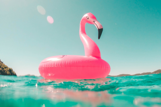 Photo of inflatable flamingo floating on warm blue sea