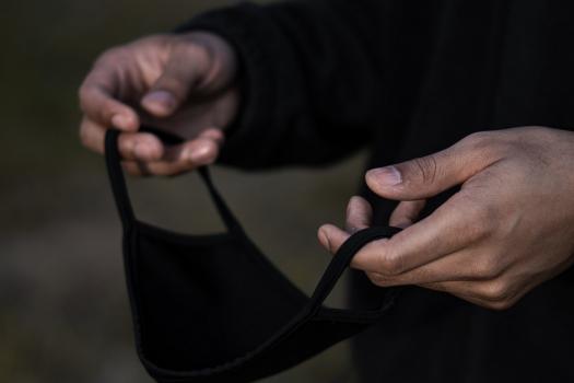 BAME man holding a face mask - cropped around mask and hands