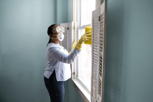 Asian woman in face mask cleaning window