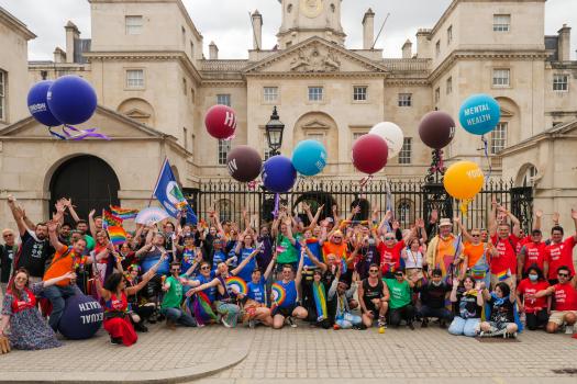 Group shot of METRO after London Pride. Staff are wearing different coloured t-shirts and holding huge balloons